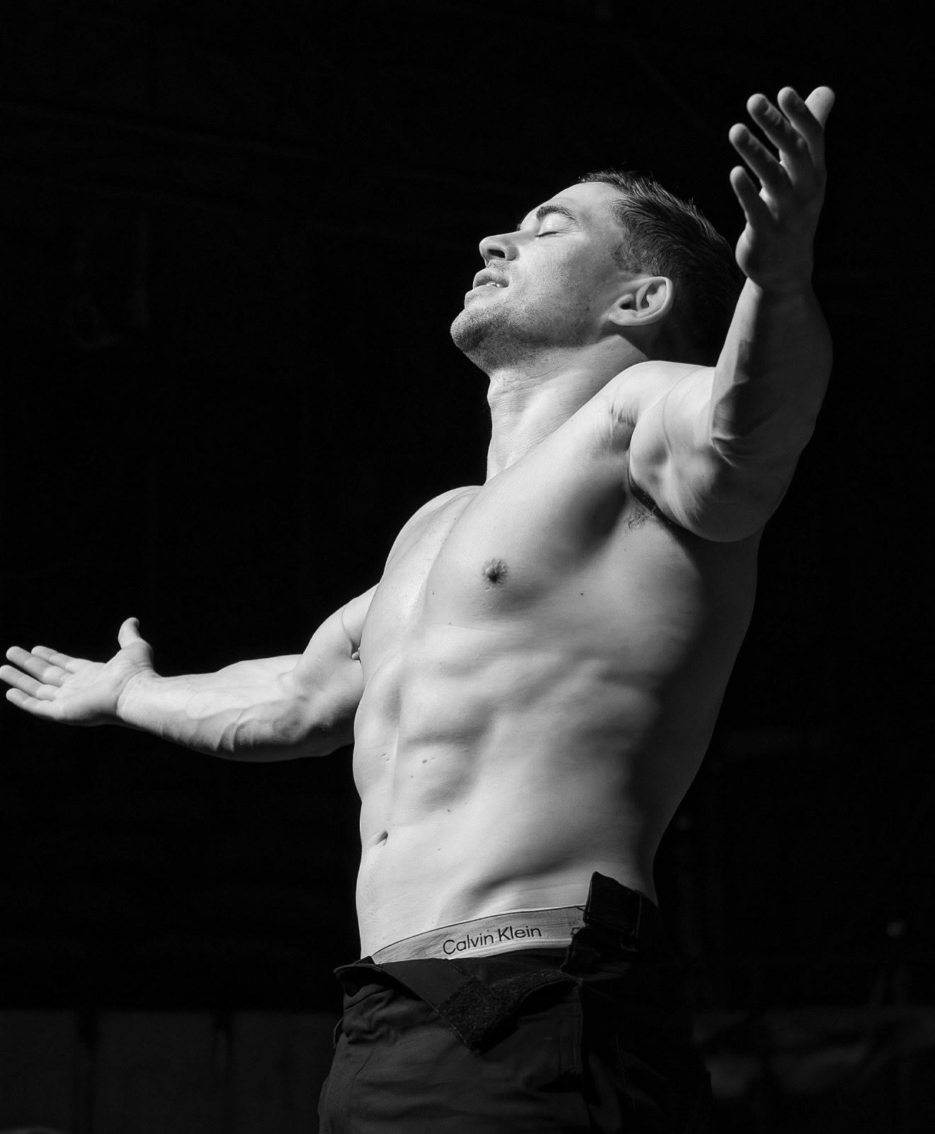 Will Parfitt shirtless in black and white, head thrown back and arms flung open