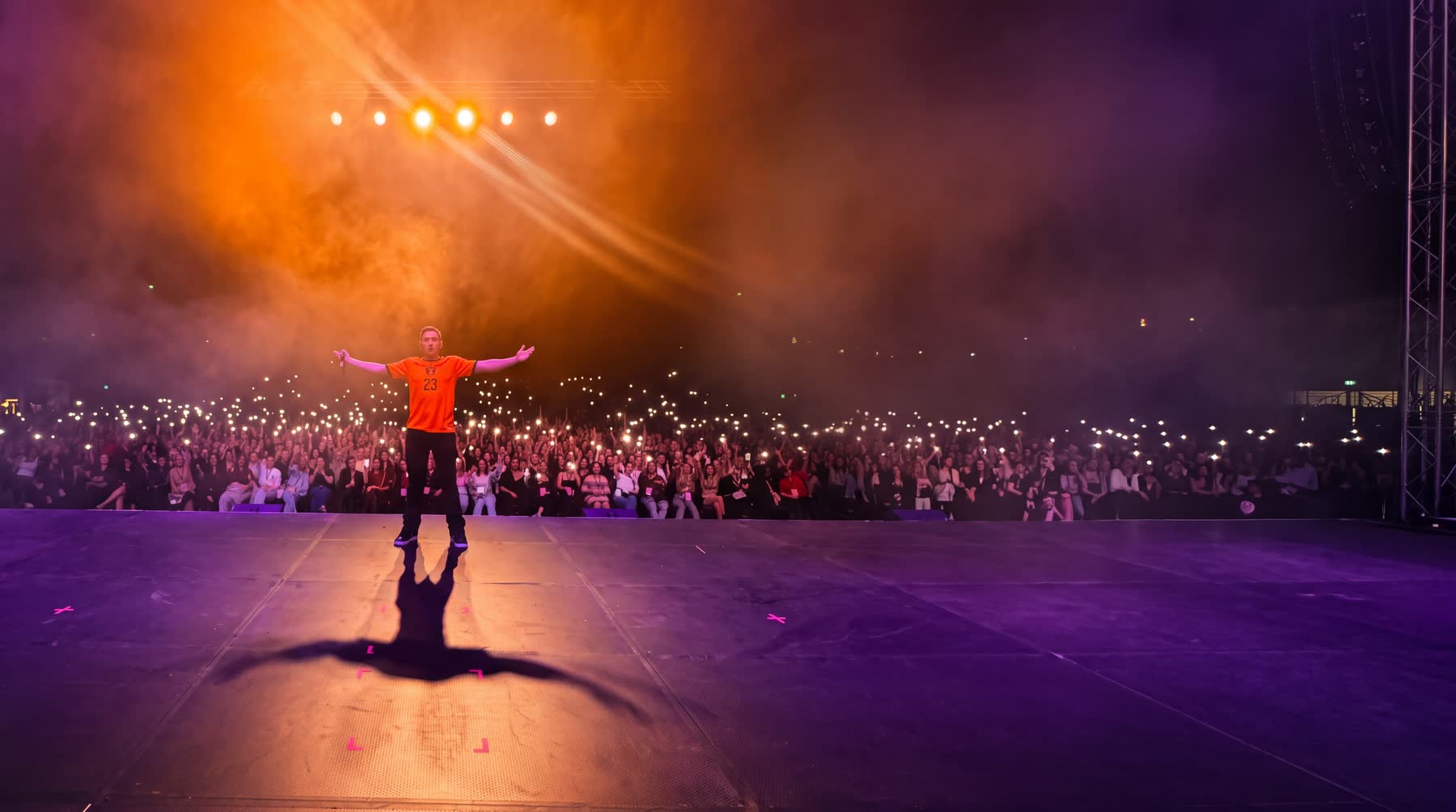 A full arena in the dark, phone lights held up across the crowd