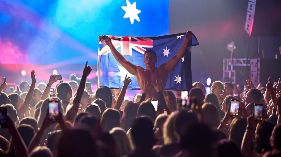 Will Parfitt holding the Australian flag in a packed arena tour audience